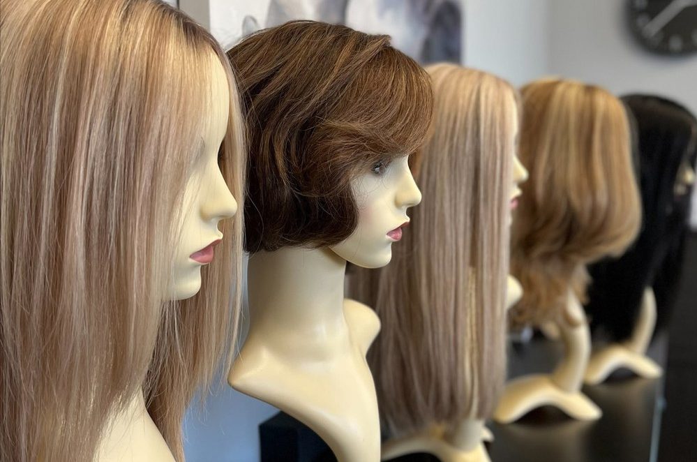 A row of mannequins with different colored hair.