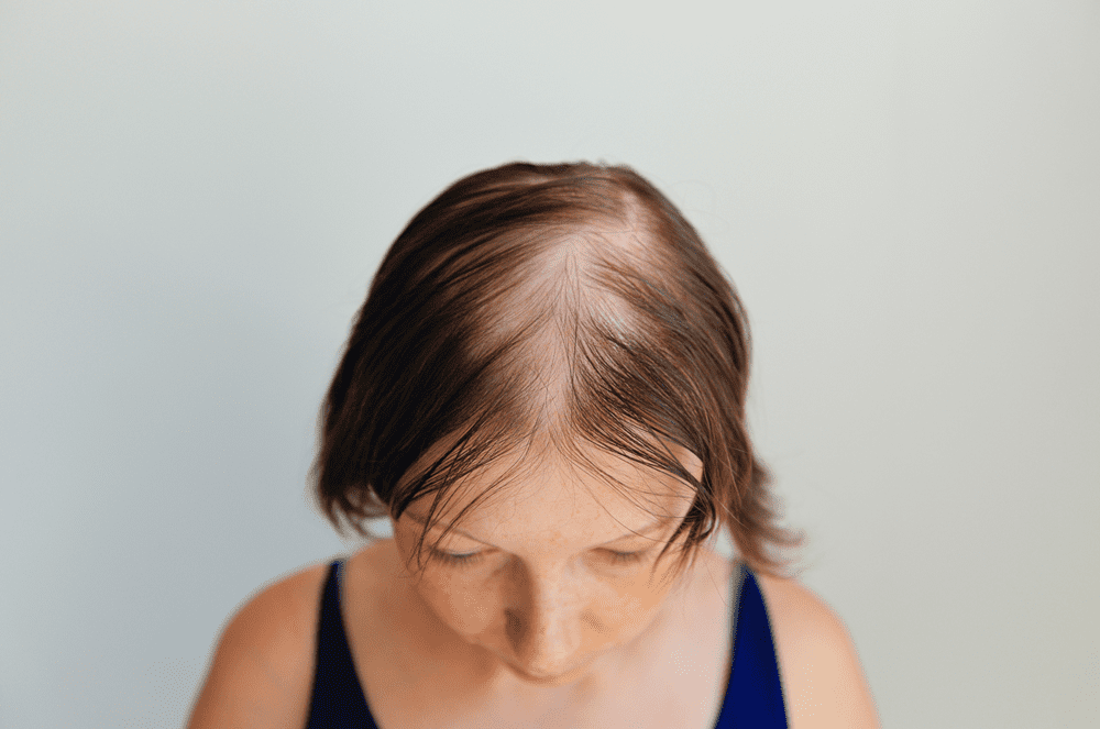 A woman with brown hair and blue top looking down.